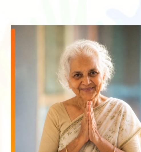 An elder supported by SHE, hands folded in gratitude